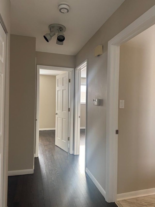 hallway featuring baseboards and dark wood-style flooring