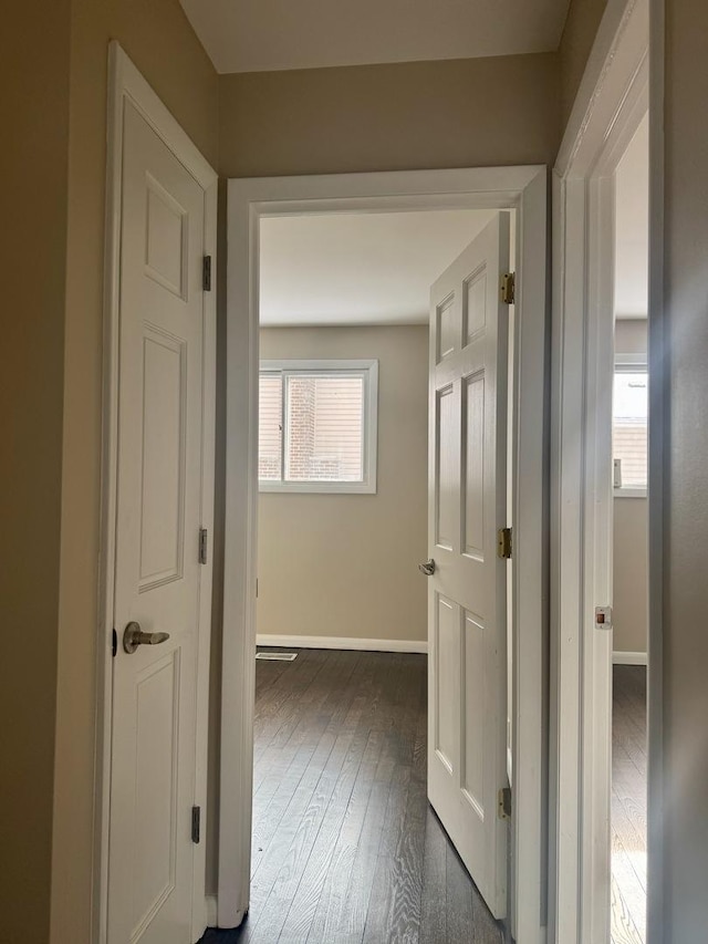 hallway with wood-type flooring, plenty of natural light, and baseboards