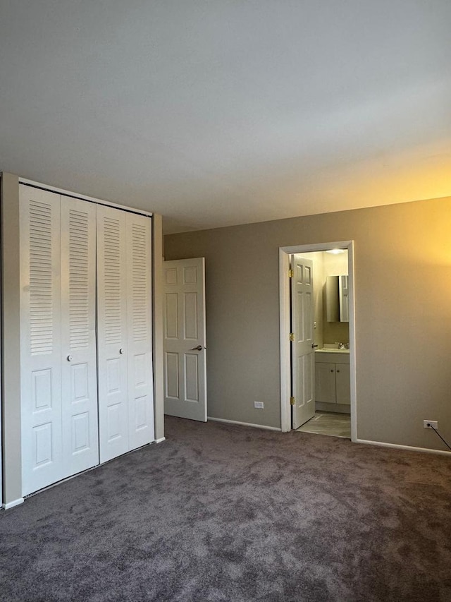 unfurnished bedroom with a closet, baseboards, carpet flooring, and ensuite bathroom