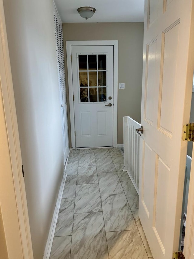 doorway to outside with marble finish floor and baseboards