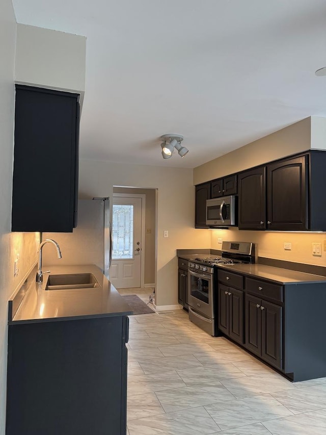 kitchen with baseboards, appliances with stainless steel finishes, and a sink