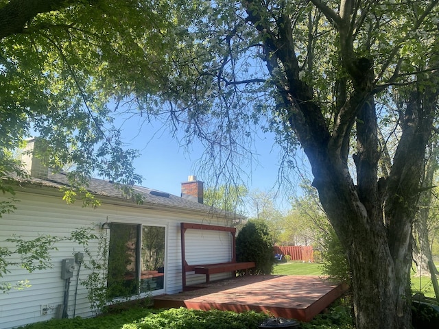 view of side of property with a chimney, a wooden deck, and fence