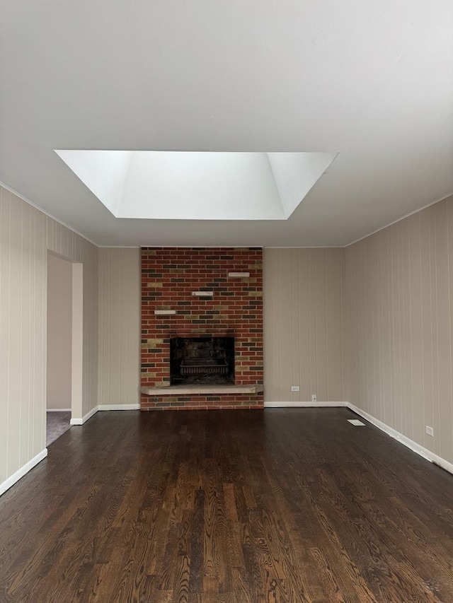 unfurnished living room with a brick fireplace, baseboards, and dark wood-type flooring