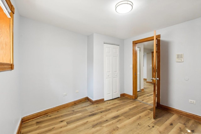 unfurnished bedroom with a closet, light wood-type flooring, and baseboards