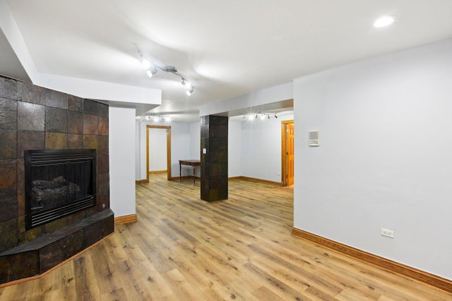 living area with light wood finished floors, a fireplace, rail lighting, and baseboards