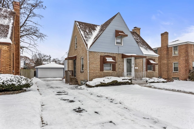 view of front of home with a garage, brick siding, and an outdoor structure