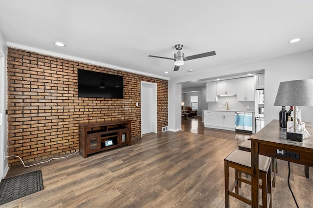 living area featuring ceiling fan, brick wall, dark wood-type flooring, and recessed lighting