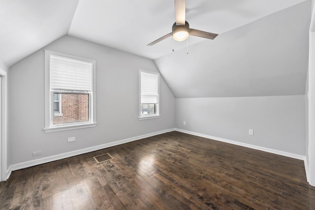 additional living space featuring baseboards, visible vents, lofted ceiling, ceiling fan, and dark wood-type flooring