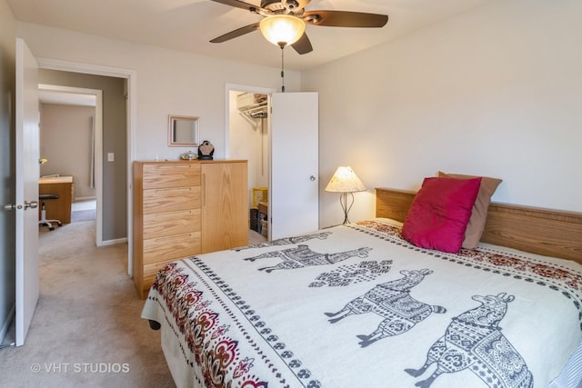 bedroom featuring a wall unit AC, a spacious closet, a ceiling fan, and light colored carpet