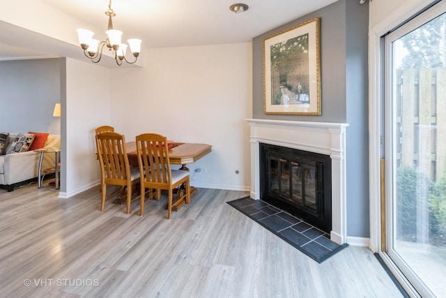 dining area featuring baseboards, a chandelier, wood finished floors, and a glass covered fireplace