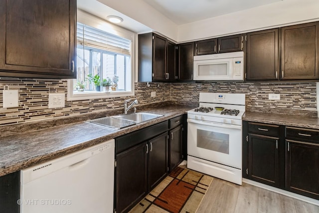 kitchen with tasteful backsplash, dark countertops, white appliances, and a sink