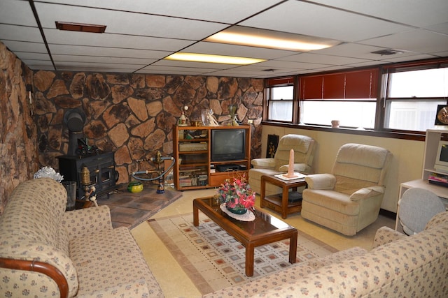 living area featuring visible vents, a paneled ceiling, and a wood stove