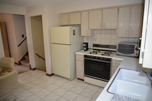 kitchen featuring white appliances, light tile patterned floors, decorative backsplash, light countertops, and a sink