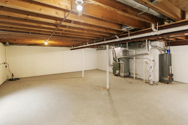 unfinished basement featuring heating unit, water heater, and visible vents