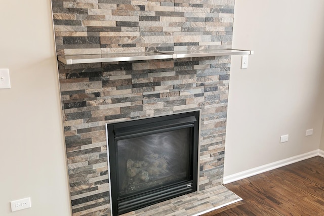 interior details featuring a glass covered fireplace, baseboards, and wood finished floors