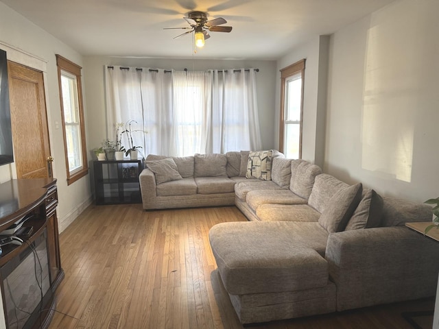 living room with baseboards, a ceiling fan, and light wood-style floors