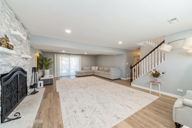 living area featuring wood finished floors, visible vents, recessed lighting, a fireplace, and stairs