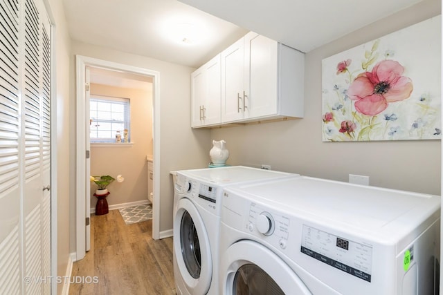 laundry area with cabinet space, washer and dryer, baseboards, and light wood-style floors