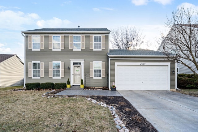 colonial-style house featuring driveway, an attached garage, and a front yard