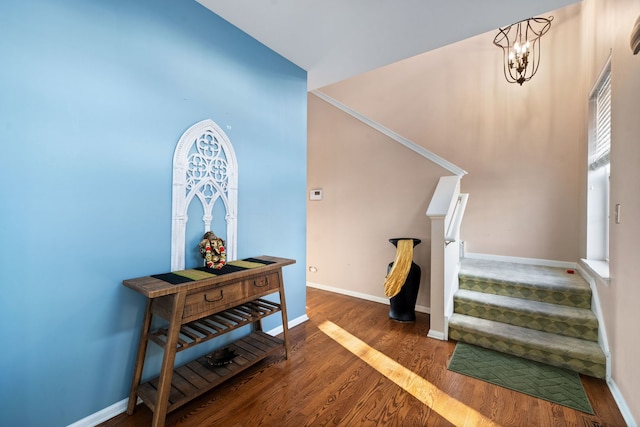 stairway with an inviting chandelier, baseboards, and wood finished floors