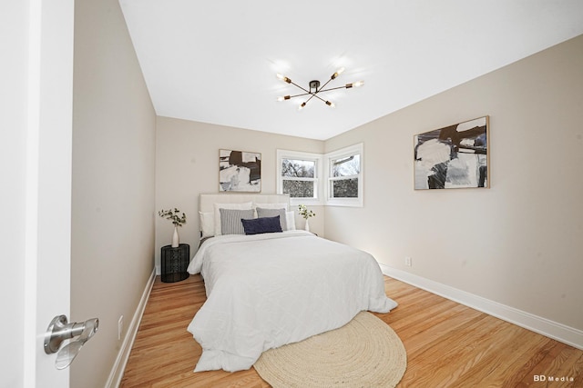 bedroom with wood finished floors, baseboards, and a chandelier