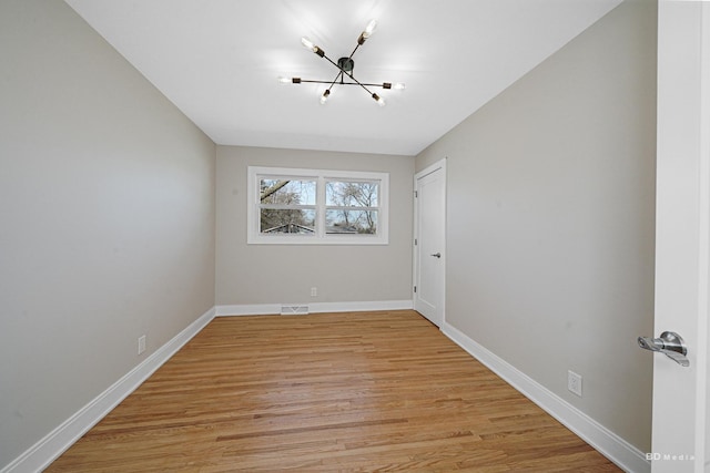 unfurnished room with a notable chandelier, light wood-style flooring, visible vents, and baseboards