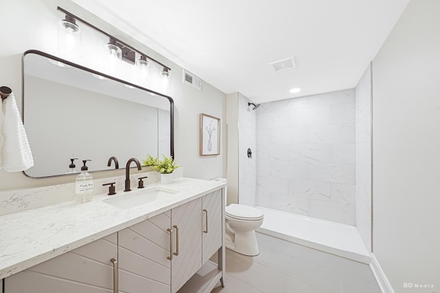 bathroom featuring vanity, toilet, visible vents, and tiled shower