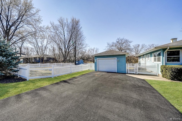 detached garage featuring aphalt driveway and fence