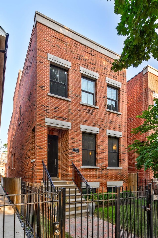 view of front of house featuring a fenced front yard, a gate, and brick siding