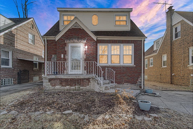 view of front of property featuring a shingled roof, aphalt driveway, and brick siding