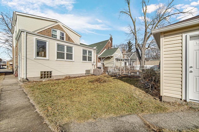 view of home's exterior featuring fence and a lawn