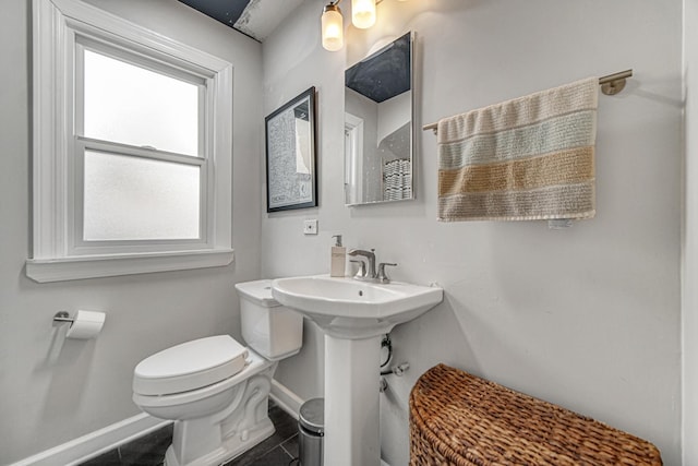 bathroom with toilet, tile patterned flooring, baseboards, and a sink