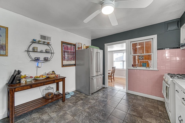 kitchen featuring white range with gas stovetop, baseboards, ceiling fan, freestanding refrigerator, and light countertops