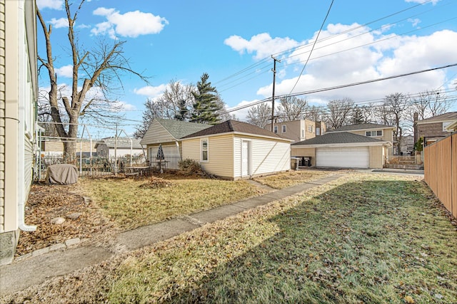 view of yard featuring a garage, fence, and an outbuilding