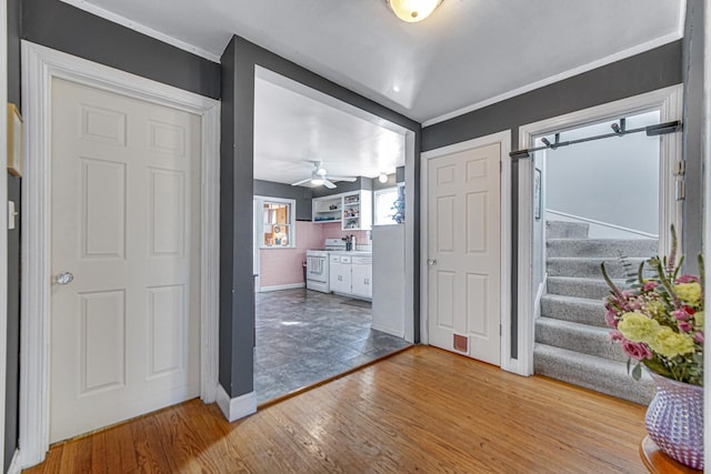 entrance foyer with wood finished floors, visible vents, baseboards, ornamental molding, and stairway