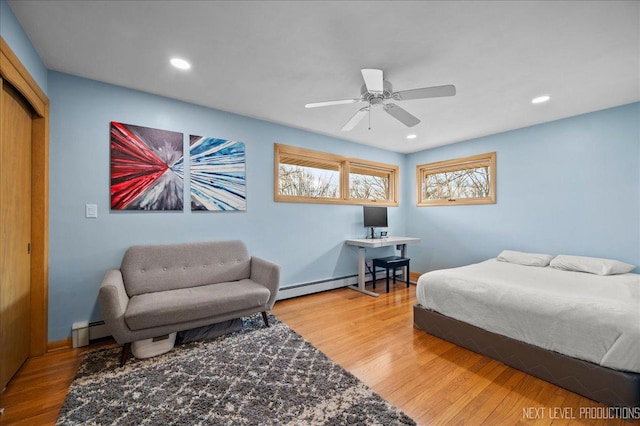 bedroom with a baseboard radiator, baseboards, recessed lighting, and wood finished floors