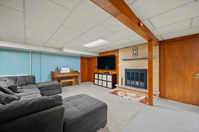 living room with carpet floors, a brick fireplace, and wood walls