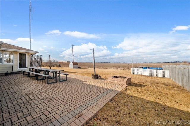 view of patio / terrace featuring a storage shed, an outdoor fire pit, an outbuilding, fence private yard, and outdoor dining area