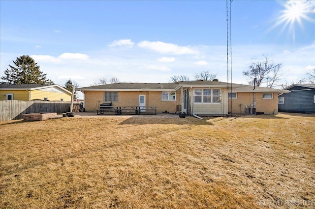 rear view of property featuring a lawn, fence, cooling unit, a patio area, and brick siding