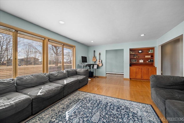 living room featuring built in shelves, recessed lighting, a baseboard heating unit, wood finished floors, and baseboards