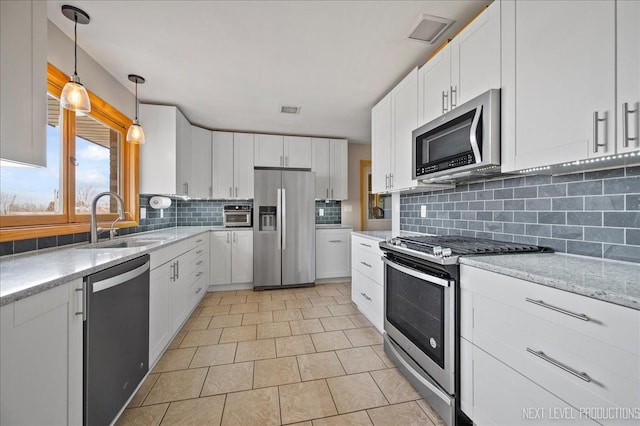 kitchen featuring visible vents, decorative backsplash, stainless steel appliances, white cabinetry, and a sink