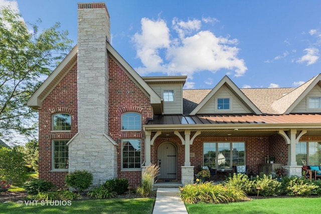 view of front of property featuring a shingled roof, a chimney, metal roof, a standing seam roof, and brick siding