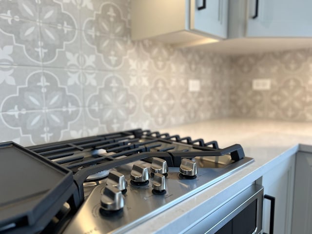 interior details with stainless steel gas stovetop, decorative backsplash, and light countertops