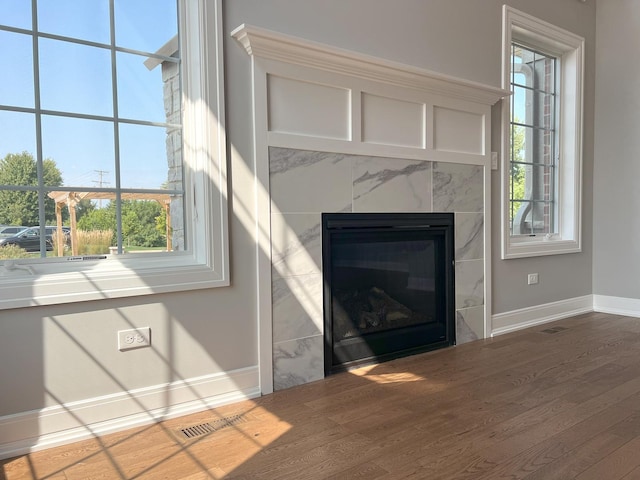 room details featuring baseboards, a premium fireplace, visible vents, and wood finished floors