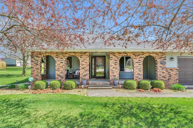 view of front facade with roof with shingles, an attached garage, covered porch, a front lawn, and brick siding