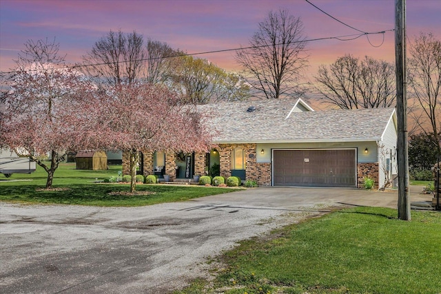 view of front of home with driveway, brick siding, a front lawn, and an attached garage