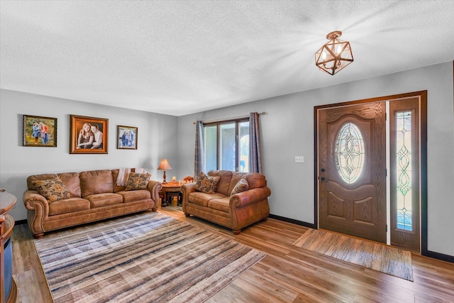 interior space with a textured ceiling, wood finished floors, and baseboards