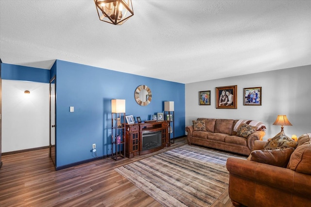 living area with a textured ceiling, baseboards, a fireplace, and wood finished floors