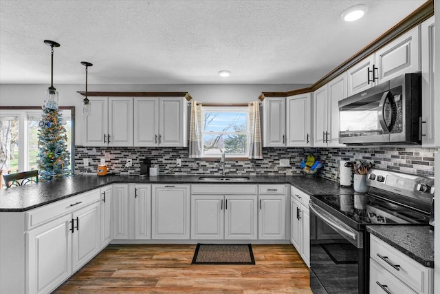 kitchen featuring appliances with stainless steel finishes, dark countertops, a sink, and a peninsula