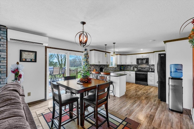 dining area with light wood-style flooring, an inviting chandelier, a textured ceiling, a wall mounted air conditioner, and baseboards